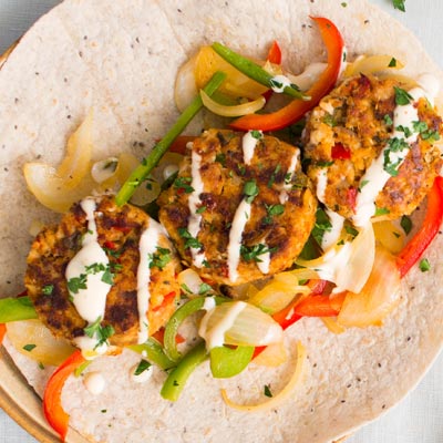 Cajun salmon cake wrap with sautéed peppers and creamy paprika sauce dripping