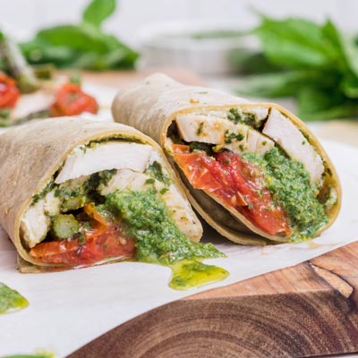 Sliced pesto chicken wrap showing layers of roasted tomatoes