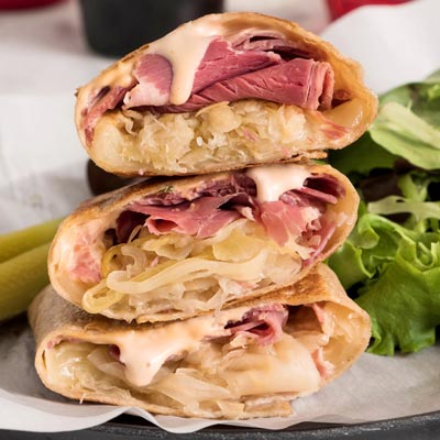 Grilled Reuben wrap showing melted Swiss cheese