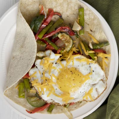 Breakfast wrap filled with colorful roasted vegetables topped with a perfectly cooked egg